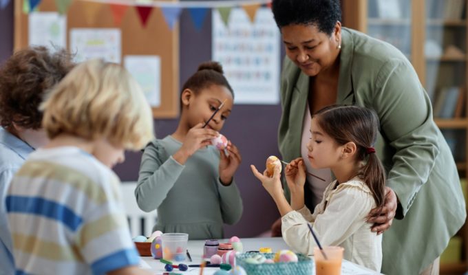 Diverse group of little kids painting Easter eggs enjoying arts and crafts class